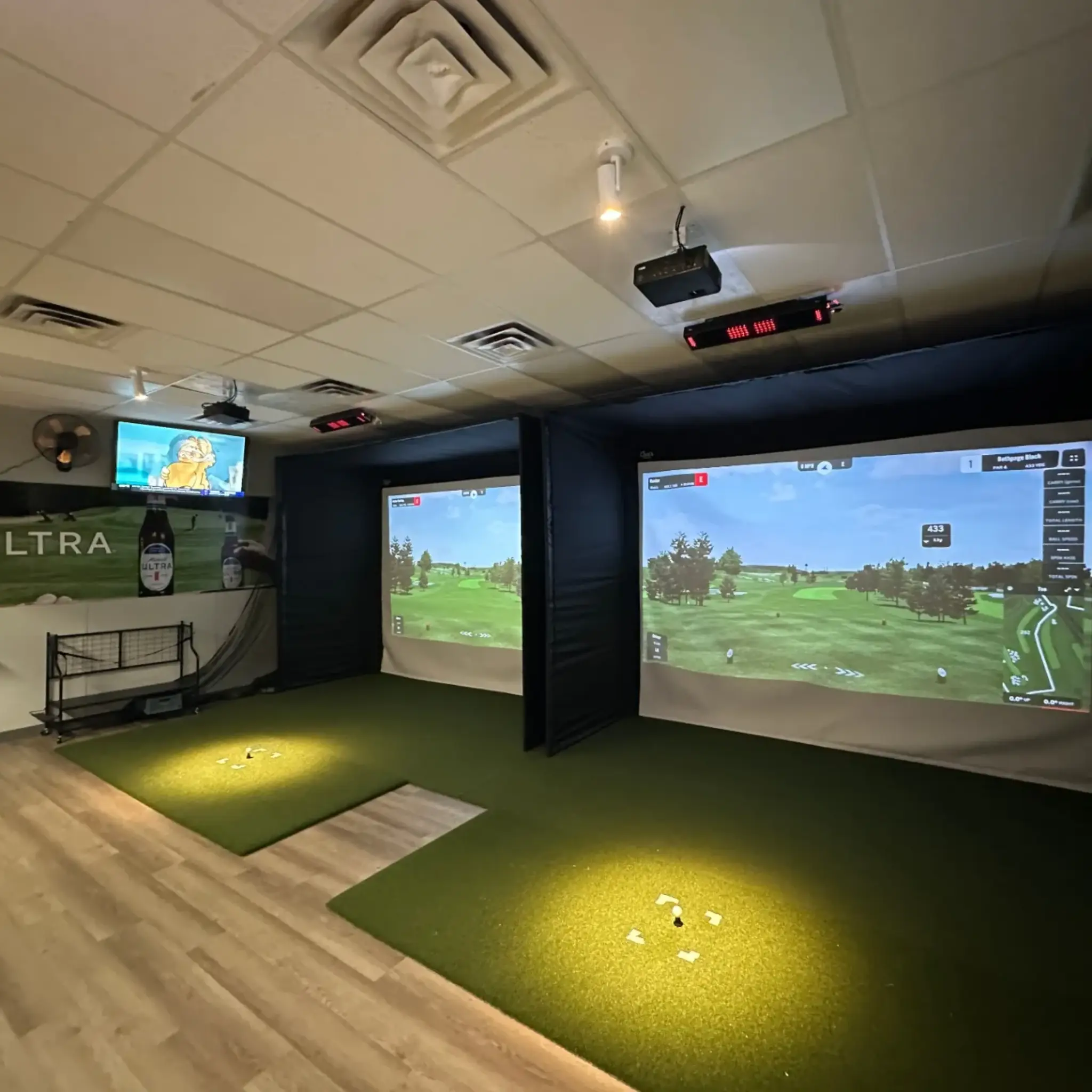 A modern golf simulator room with two large projection screens