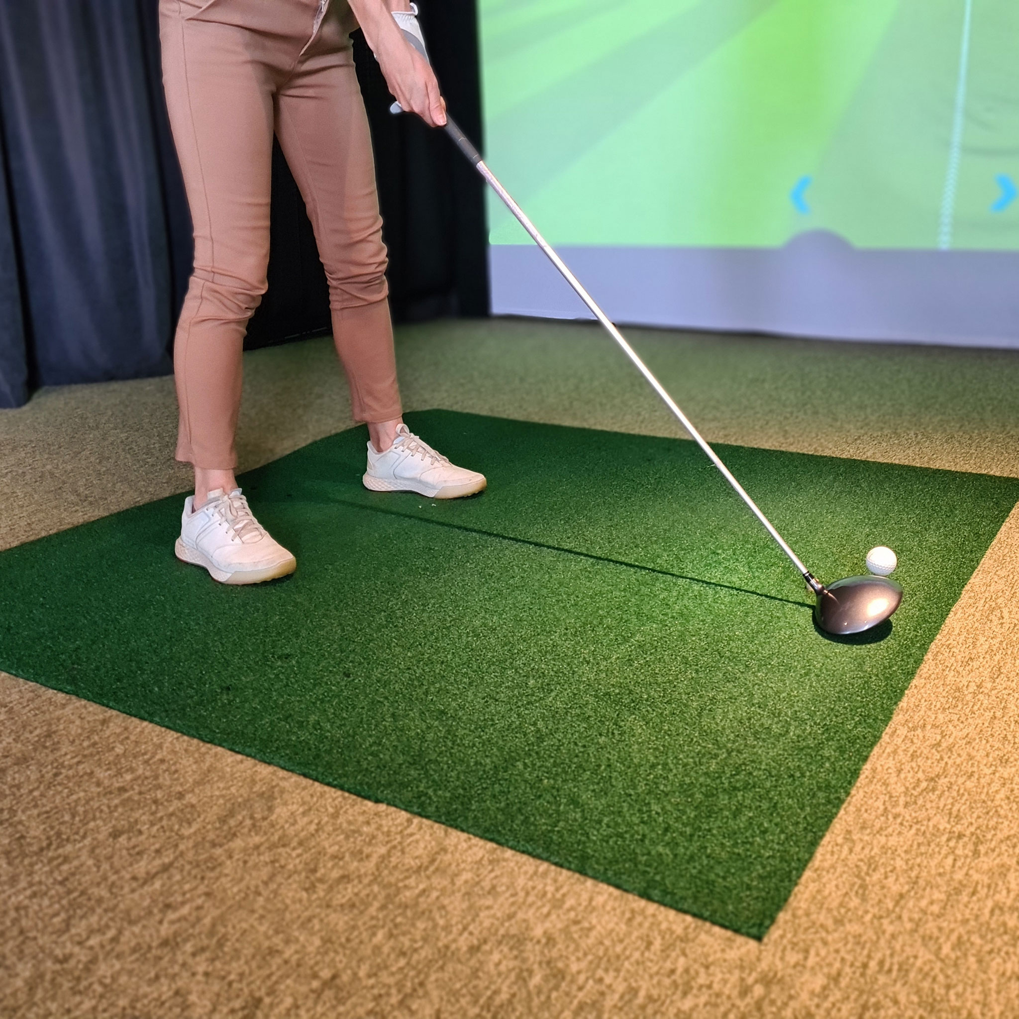 Girl golf player plays golf indoors. Golf driving range with simulator screen