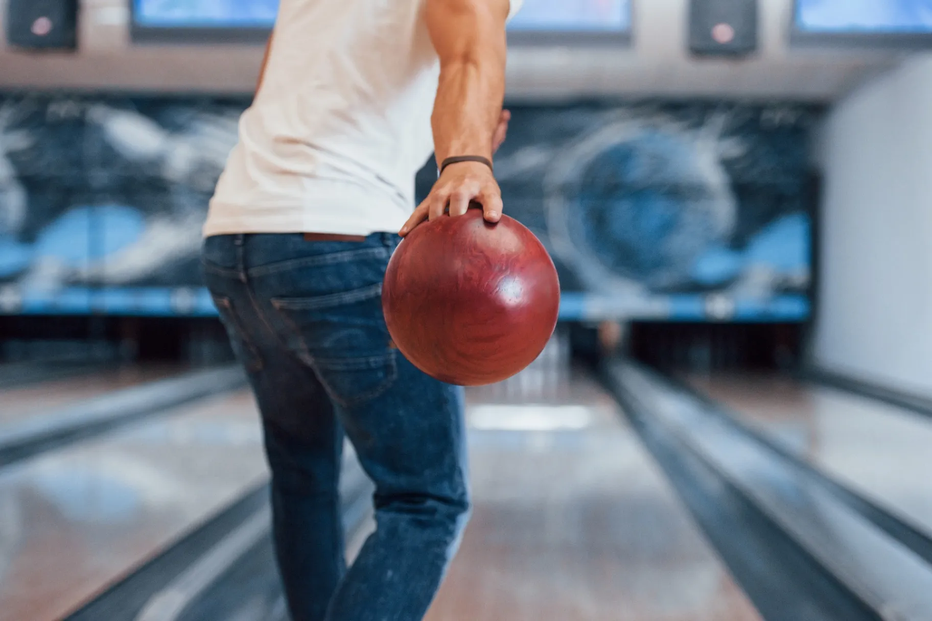 Rear particle view of man in casual clothes playing bowling in the club